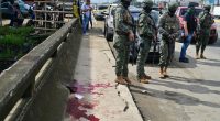 Military officers stand near bloodstains at a crime scene.