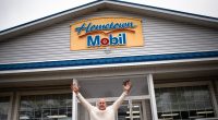 Man celebrating in front of Hometown Mobil gas station that sold a winning Mega Millions lottery ticket.