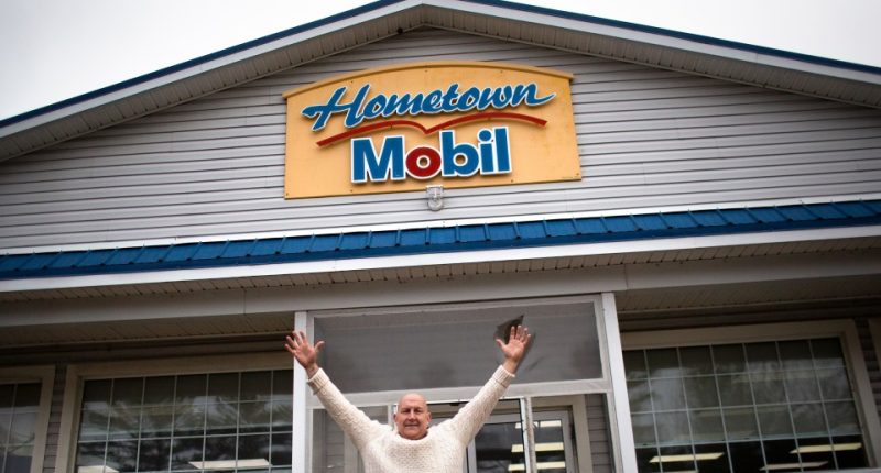 Man celebrating in front of Hometown Mobil gas station that sold a winning Mega Millions lottery ticket.