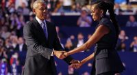 Barack and Michelle Obama holding hands on stage.