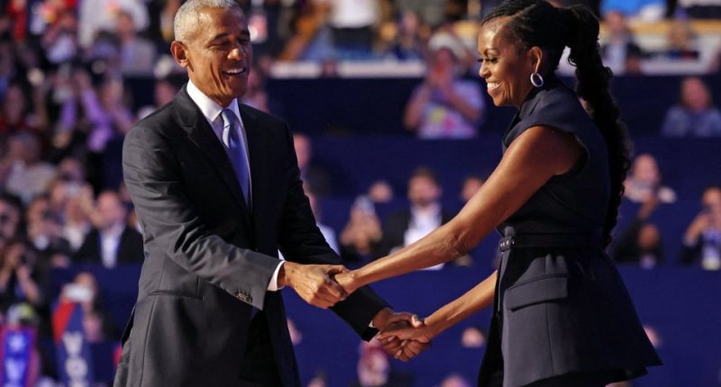 Barack and Michelle Obama holding hands on stage.
