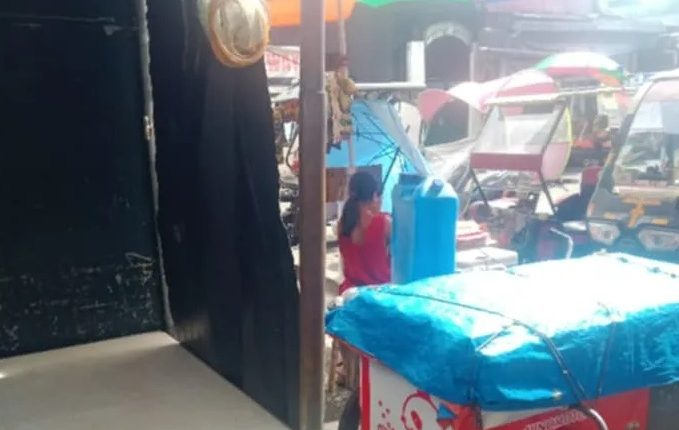Philippines market scene with food cart and table.