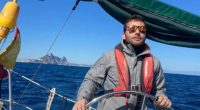 Man steering a sailboat at sea.