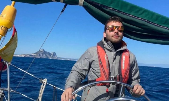 Man steering a sailboat at sea.