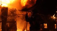 Firefighter silhouetted against a burning building.