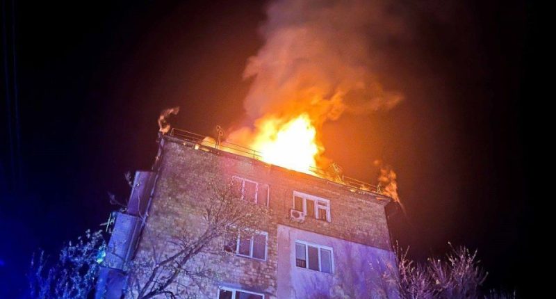 Fire engulfing the roof of a building at night.