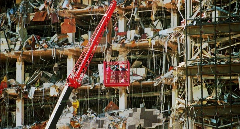 Rescue workers in a lift amidst rubble from a bombed building.