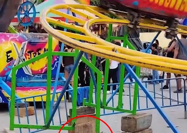 Children's fairground ride precariously balanced on wooden logs.