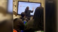 Teacher writing on interactive whiteboard in classroom.