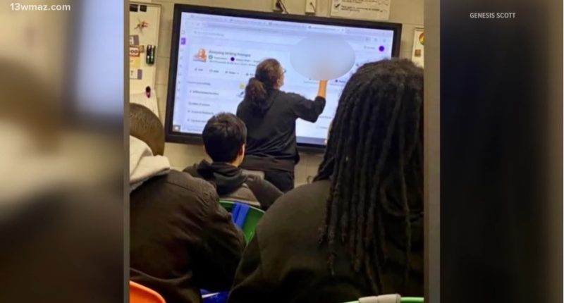 Teacher writing on interactive whiteboard in classroom.