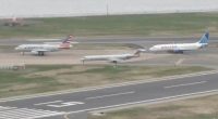 Three airplanes on an airport tarmac; one American Airlines plane, one United Airlines plane, and one American Airlines regional jet.