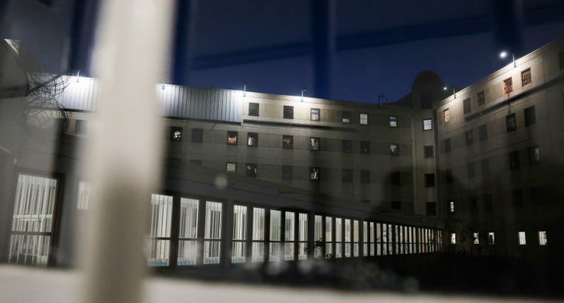 Night view of prison cells through a window.