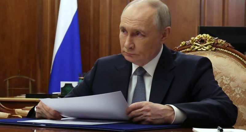 Vladimir Putin reviewing documents at a meeting.