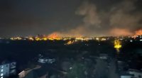 Nighttime view of fires and smoke over a city.