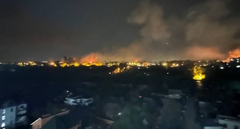 Nighttime view of fires and smoke over a city.