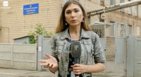 A Ukrainian journalist reporting outside a building.