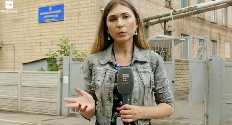 A Ukrainian journalist reporting outside a building.