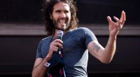 Russell Brand speaking into a microphone at a rally.