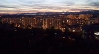 Nighttime view of city buildings and distant mountains.