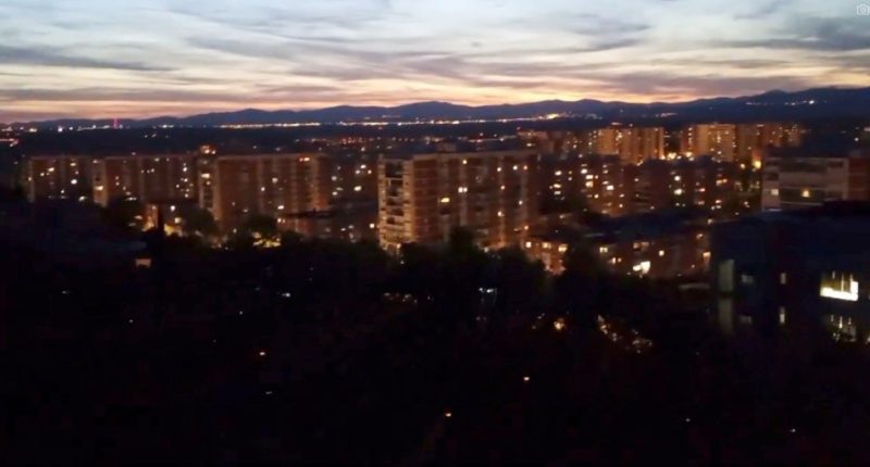 Nighttime view of city buildings and distant mountains.