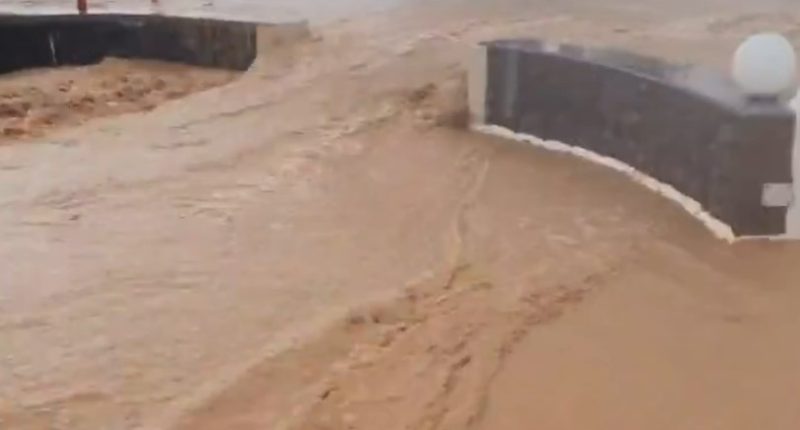 Flooded parking lot with a car driving through.