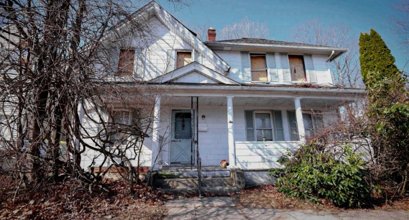 A white house with boarded-up windows.