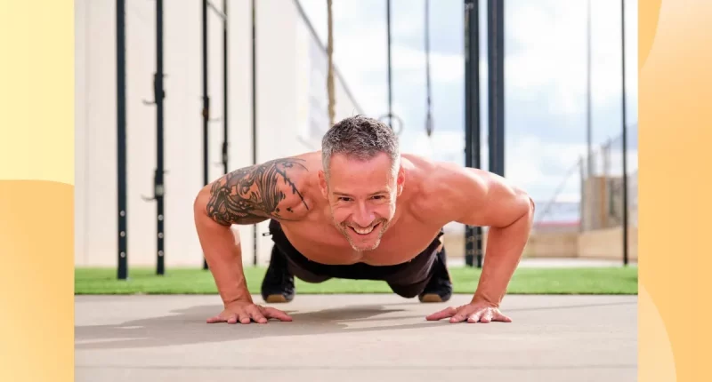 fit, muscular man doing pushups outdoors on sunny day by turf