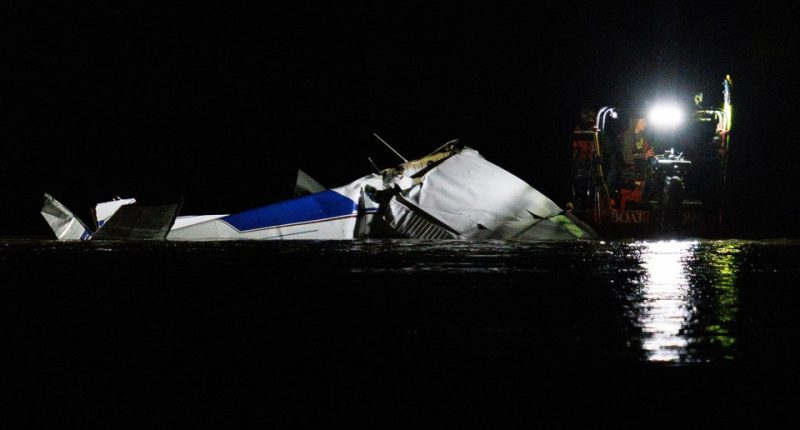 Emergency crews at night responding to a plane crash in a river.