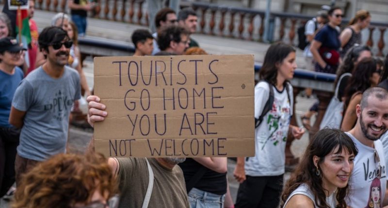 BARCELONA, CATALONIA, SPAIN - 2024/07/06: An anti-tourism placard is seen during the demonstration. More than 3,000 people demonstrated against the tourist overcrowding suffered by the city of Barcelona and in favor of tourism reduction policies. The demonstration involved symbolically closing hotel establishments, bars and restaurants while heading towards Barceloneta, one of the neighborhoods that suffers the most from the presence of tourism. (Photo by Paco Freire/SOPA Images/LightRocket via Getty Images)