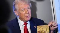 Donald Trump holding a gold card with his image on it.