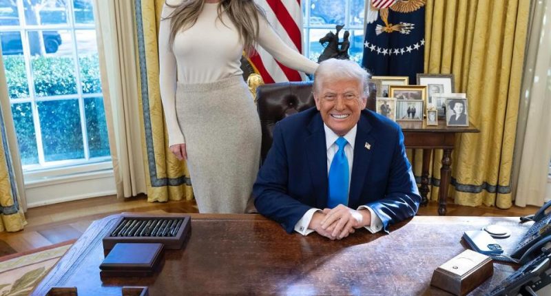 Donald Trump seated at his desk with Margo Martin standing behind him.