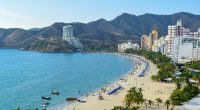 Beach in Santa Marta, Colombia, with hotels and people.