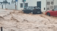 Flooded street with cars partially submerged.