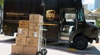 UPS truck with a hand truck full of TOMS shoe boxes.