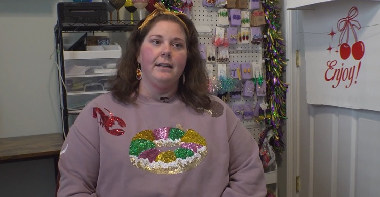 A woman wearing a Mardi Gras-themed sweatshirt discusses issues with the USPS.