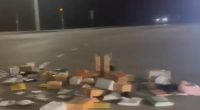 Scattered USPS packages on a road at night.