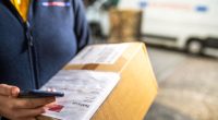 Delivery person holding a package and smartphone.