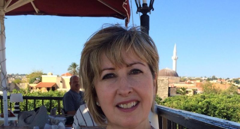 Woman on a patio with a view of a town and a mosque.