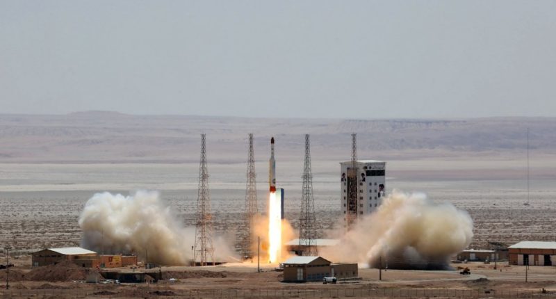 Satellite rocket launching from a desert launchpad.
