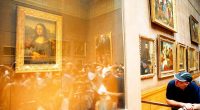 A man views the Mona Lisa through a protective glass case in a museum.