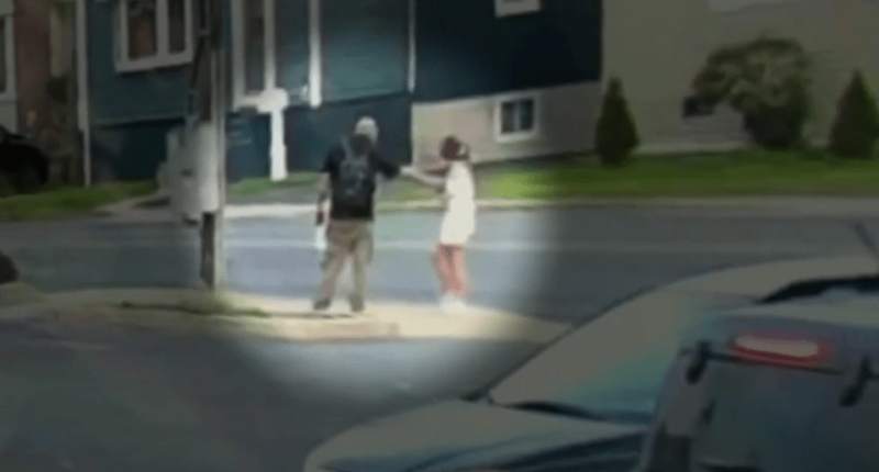 Two people interacting on a street corner.