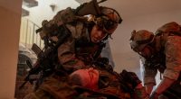 Still from *Warfare*, showing soldiers tending to a wounded comrade.