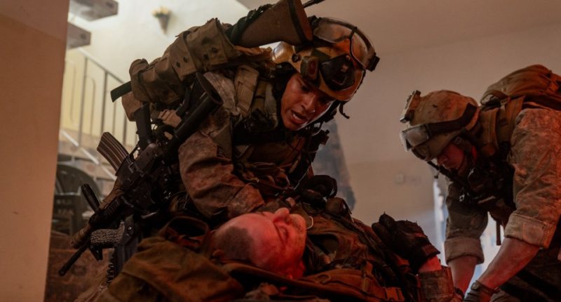 Still from *Warfare*, showing soldiers tending to a wounded comrade.