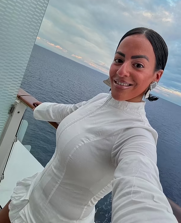 Woman in white dress on cruise ship balcony.