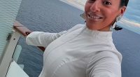 Woman in white dress on cruise ship balcony.
