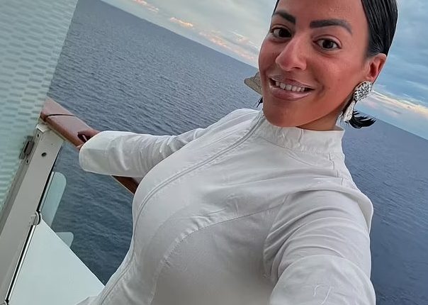 Woman in white dress on cruise ship balcony.