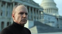 a bald man stands in front of the capitol building