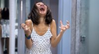 Woman in polka dot dress shouting at her reflection in a mirror.