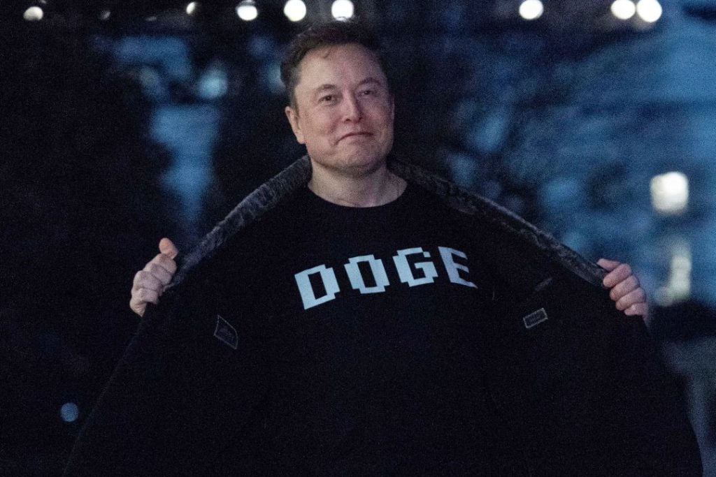 Elon Musk flashes his T-shirt that reads "DOGE"