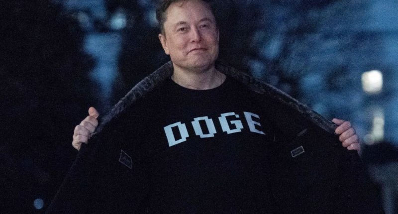 Elon Musk flashes his T-shirt that reads "DOGE"